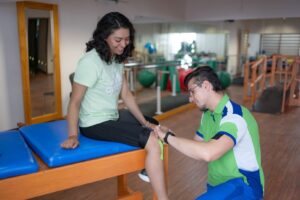 Fisioterapeuta dando masaje en la rodilla a paciente durante sesión de fisioterapia en CDMX